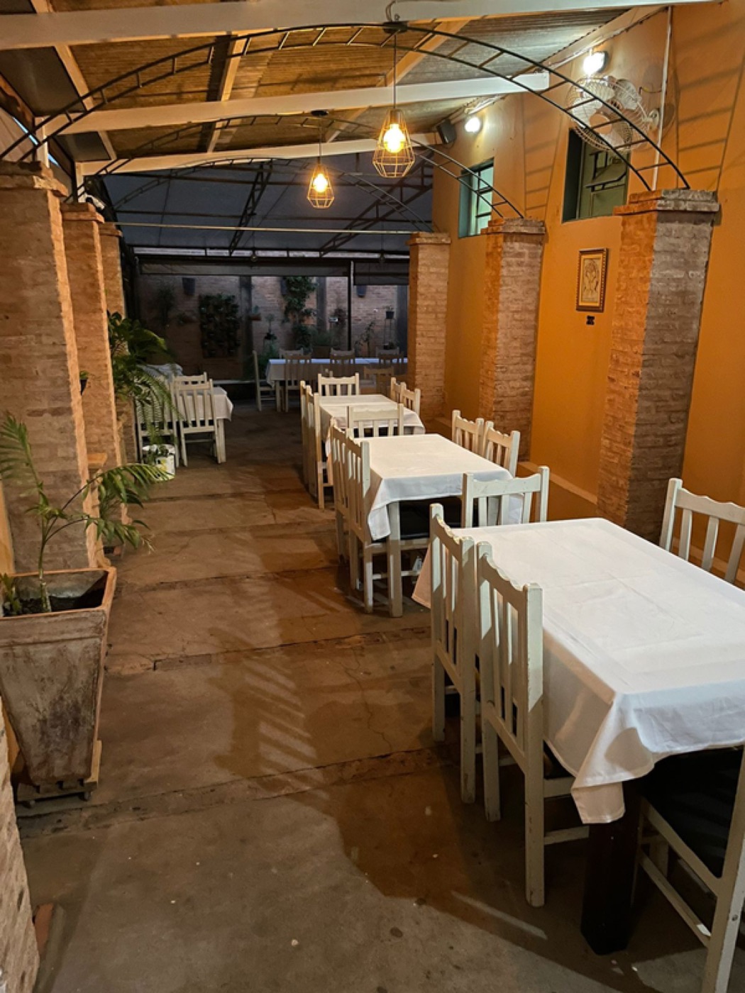 Área externa da Danluthi à noite, com mesas de toalha branca